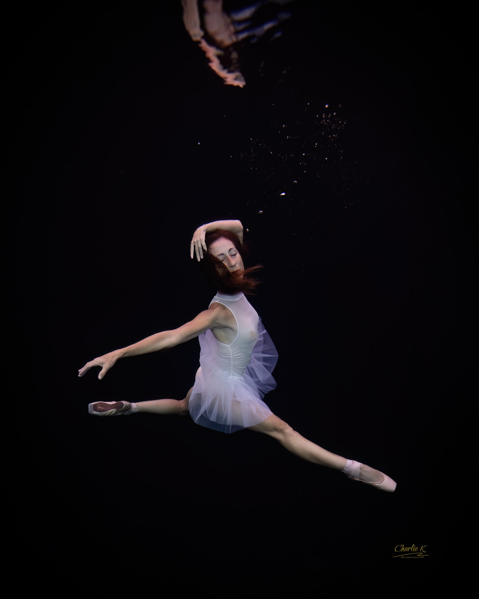 Underwater ballerina in a white tutu against black water
