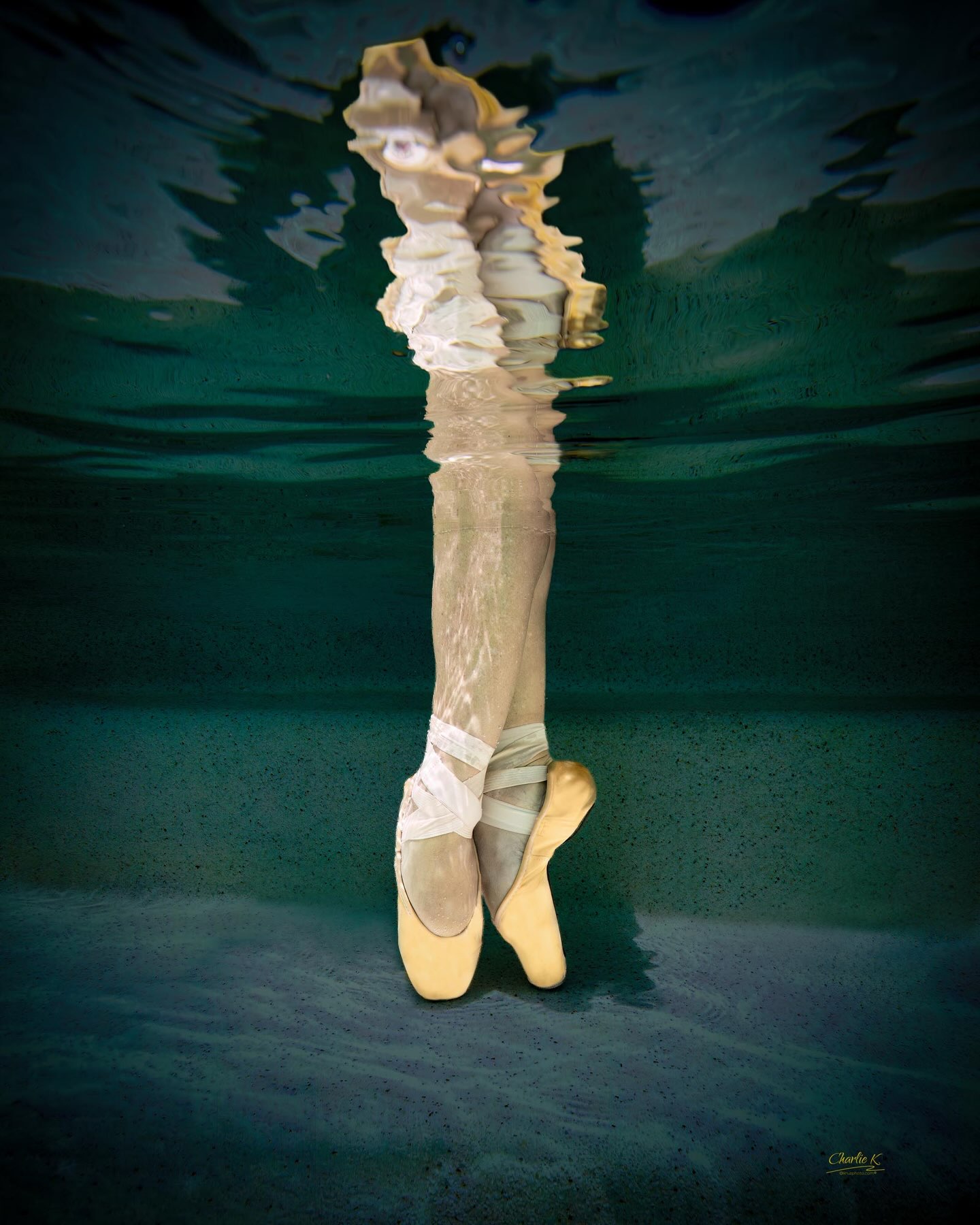 Pointe shoes meeting the mirrored surface of the water